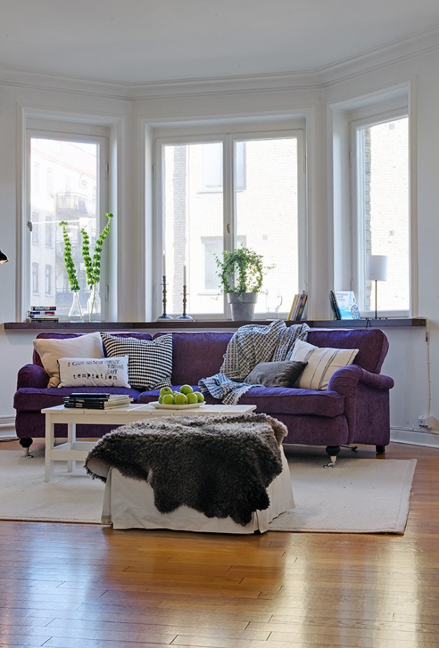 深紫色的棉质沙发，质感和舒适感并存。大大的窗户和些许的绿色盆栽点缀，就足以让整个空间温馨满意了。
