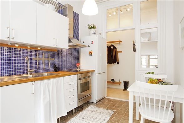 厨房的墙面采用马赛克的瓷砖设计，橱柜则是清爽的白色，很干净。