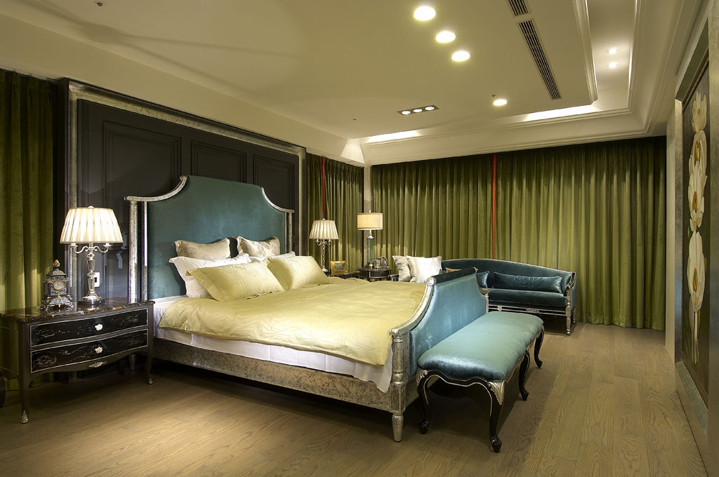 主卧室铁灰色的床头造型，利用简化的线条彰显局部银箔的低调奢华感，而铁灰色与周边窗帘选用的橄榄绿，也是非常新鲜的色彩配置法。