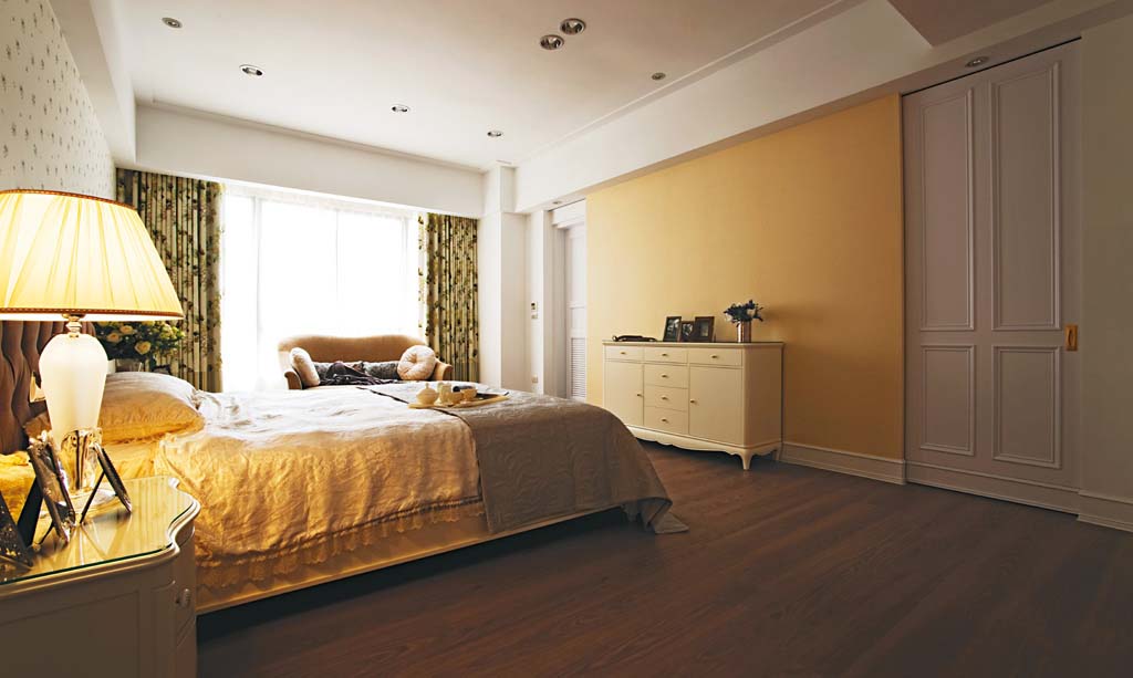 主卧室床尾将更衣间与浴室门规划於两侧，搭配米黄色壁纸与端 景柜做主墙设计。