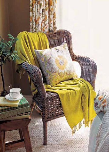 窗前的藤椅和原木质地的案几质感细腻，骨架硬朗，有效地提升了田园卧室的厚重感。随意搭配艳色的披毯，显得清新自然。