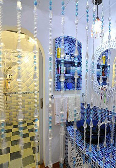 水晶珠帘隔开的是干湿分离的卫浴间。洗手台和壁龛储物柜都用蓝色马赛克装饰，让这一泓清泉般的蓝色成就水晶宫般的亮丽效果。