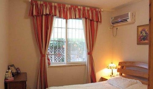 卧室设计中贯彻暖色调得田园风格，木制的床和红色的窗帘旁边床头配上欧式雕花小灯，让小卧室温馨舒适。