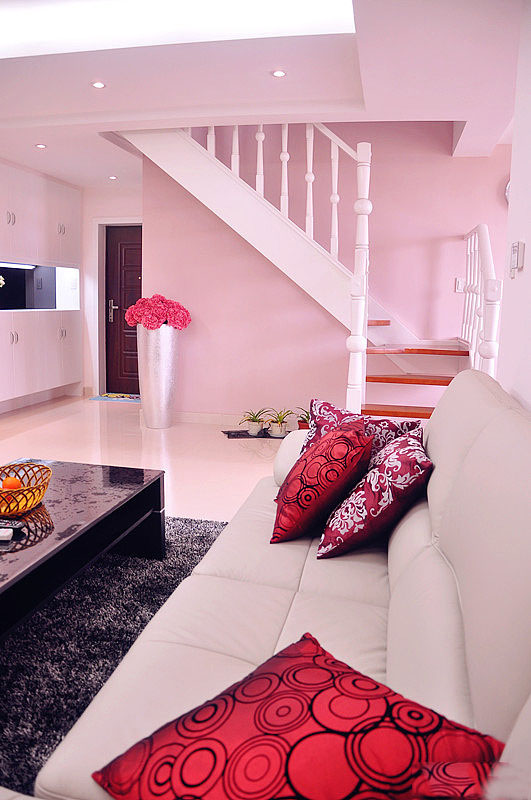 米色的沙发上摆放两三个红色的抱枕，提亮了客厅的颜色。