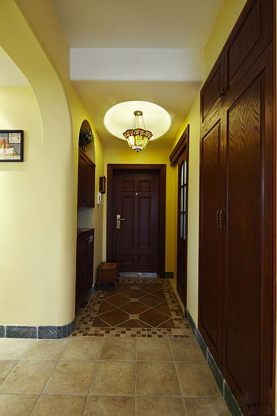 入门玄关处设计很简单，将玄关柜内嵌在玄关的墙面上，扩大了空间的使用面积。不同颜色的瓷砖来区分不同的功能区。