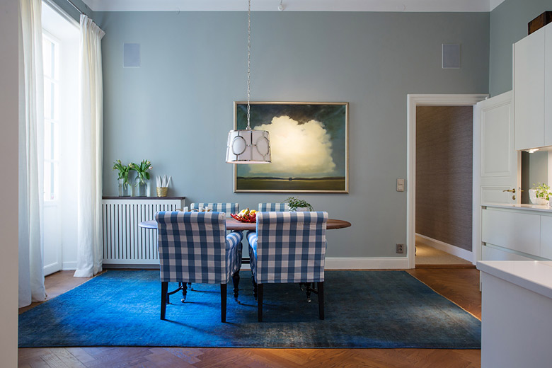 简单的餐厅，浅蓝色墙面搭配深蓝色地毯，蓝白格子的餐椅，加上墙上装饰画的点缀，明亮舒适。
