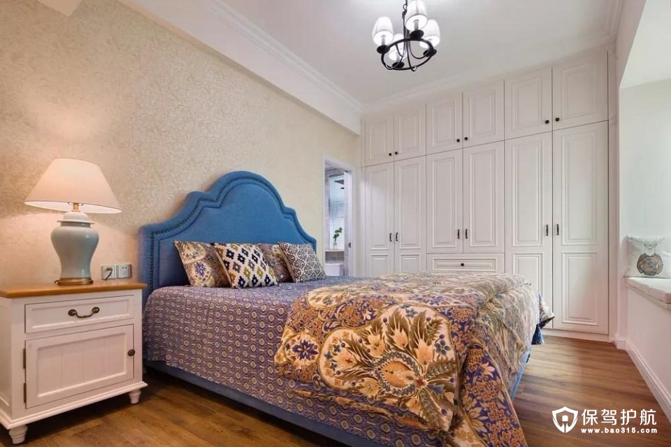 米黄色的花纹墙纸和水蓝色的床上放着各种花纹的抱枕和被子，浓浓的乡村气息。