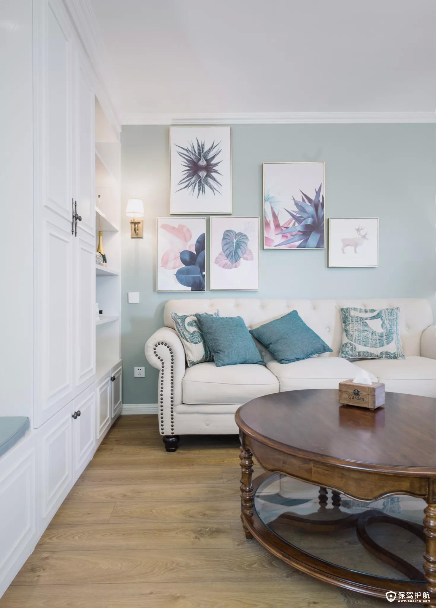 沙发墙在淡蓝色的空间基础，挂上几张清新文艺的装饰画，结合上舒适现代的美式布艺沙发，并在沙发墙角落装一盏壁灯，整个空间层次丰富、没感十足。